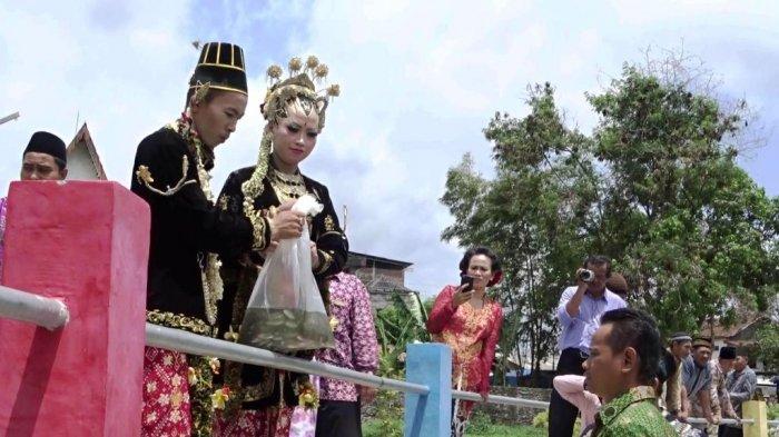 Unik, Kenakan Busana Pengantin, Dwi Muji Santoso Tebar Benih Ikan di Embung